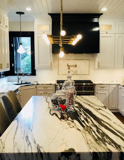 A kitchen with marble counter tops and white cabinets.