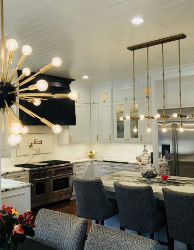 A kitchen with white cabinets and black chairs